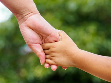 Annenin el bokeh arka plan üzerinde küçük bir kızın elini tutarak. Aşk ve Aile kavramı.