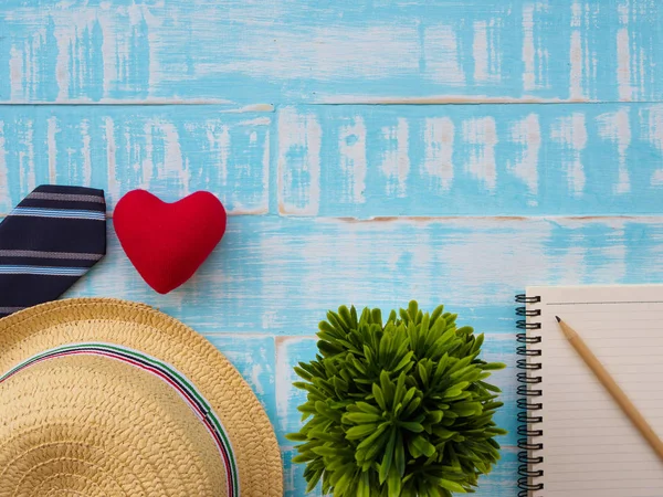 Mutlu babalar günü yazıt ile bitki, redheart, şapka, kravat, Not defteri ve kalem mavi ahşap zemin üzerinde. Babalar günü kavramı.