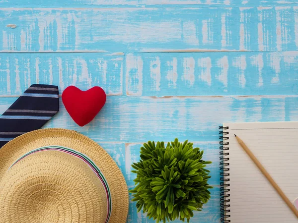 Mutlu babalar günü yazıt ile bitki, redheart, şapka, kravat, Not defteri ve kalem mavi ahşap zemin üzerinde. Babalar günü kavramı.