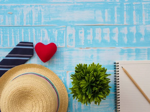 Mutlu babalar günü yazıt ile bitki, redheart, şapka, kravat, Not defteri ve kalem mavi ahşap zemin üzerinde. Babalar günü kavramı.