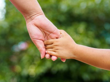 Annenin el bokeh arka plan üzerinde küçük bir kızın elini tutarak. Aşk ve Aile kavramı.