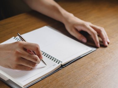 Adamın el ahşap masaüstüne yerleştirdiğiniz not defterinde yazılı kapatın. iş, eğitim kavramı.