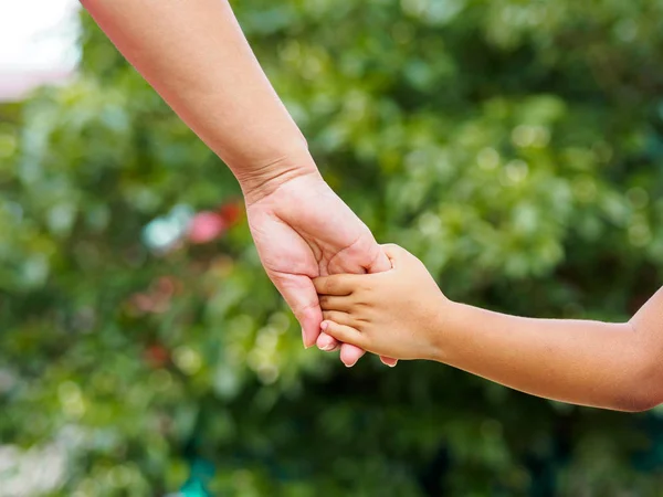Annenin el bokeh arka plan üzerinde küçük bir kızın elini tutarak. Aşk ve Aile kavramı.
