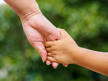 Annenin el bokeh arka plan üzerinde küçük bir kızın elini tutarak. Aşk ve Aile kavramı.