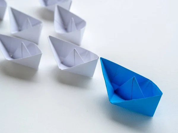 Leadership concept. Blue paper ship lead among white. One leader ship leads other ships.