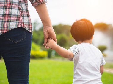 Anne ve kızı el ele parkta yürüyüş. Çocuk ve Anne Aile kavramı.