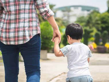 Anne ve kızı el ele parkta yürüyüş. Çocuk ve Anne Aile kavramı.