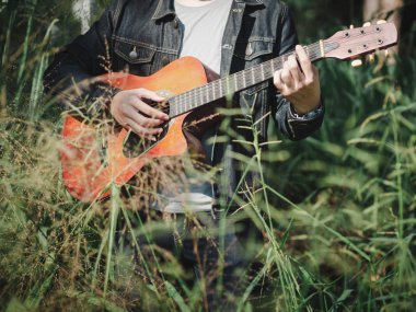 yakışıklı müzisyen çim sahası akustik gitar çalmak arka plan bulanıklık. Dünya müzik günü. müzik ve çalgı kavramı.