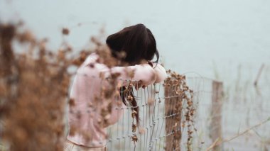 Yalnız kadın çit nehir kenarında tek başına ayakta. Yalnız, üzüntü kavramı.