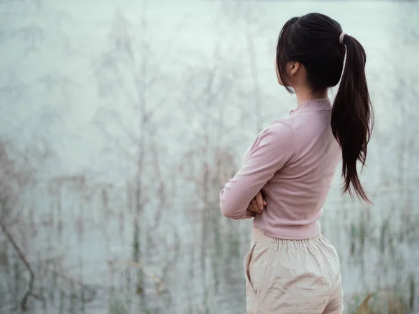 Lonely woman standing alone beside the river. Lonely, Sadness Concept.