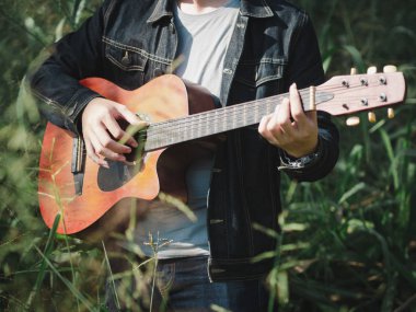 yakışıklı müzisyen çim sahası akustik gitar çalmak arka plan bulanıklık. Dünya müzik günü. müzik ve çalgı kavramı.
