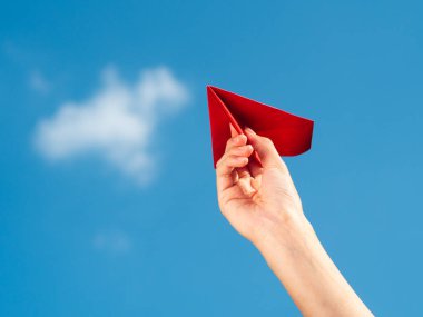 Kırmızı kağıt roket mavi gökyüzü arka plan ile tutan kadın el. Özgürlük kavramı