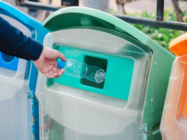 Primer plano de la mano del hombre lanzando botella de agua de plástico vacía en el reciclaje —  Fotos de Stock