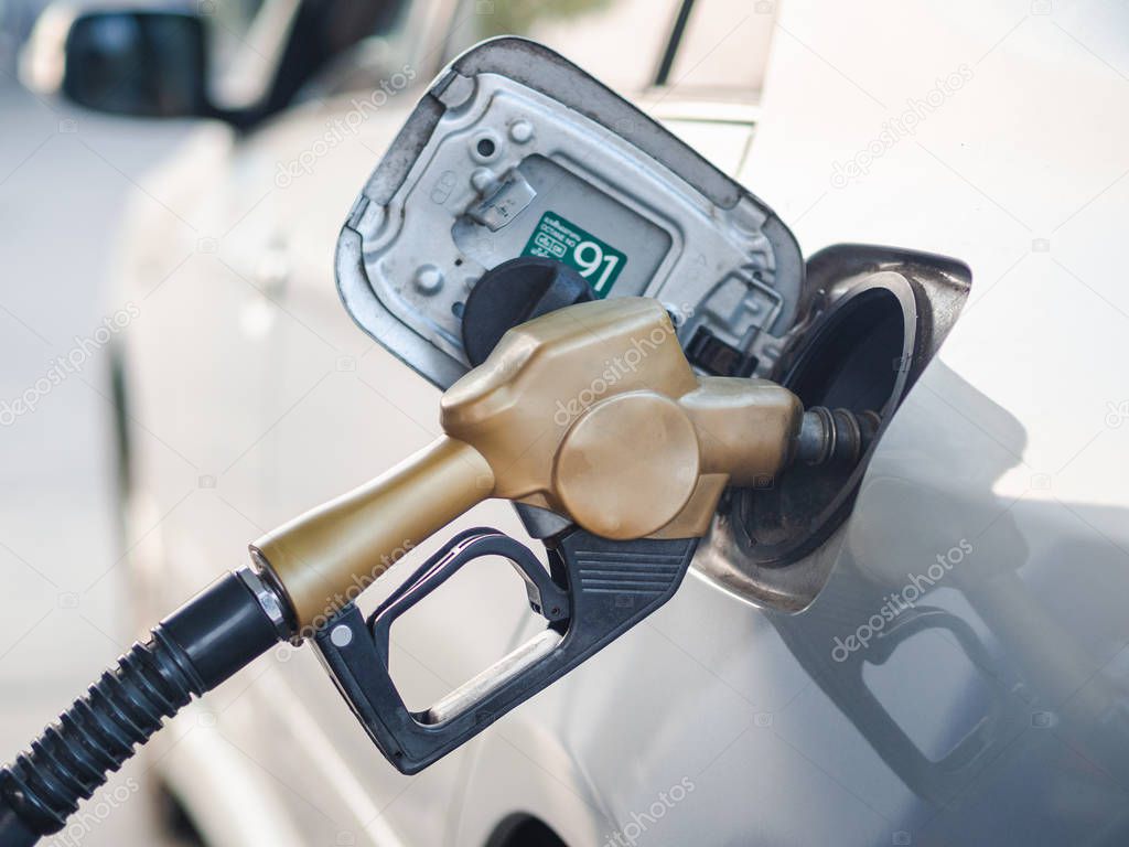 Fuel nozzle refueling a car at gas station