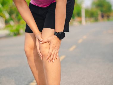 Kadın sporcu dizini acıdan tutuyor.,