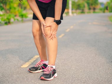 Kadın sporcu dizini acıdan tutuyor.,