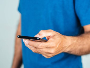 Beyaz arka planda izole edilmiş akıllı telefon kullanan genç bir adam.