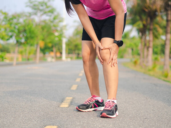 Female athlete runner holding her Knee in pain,