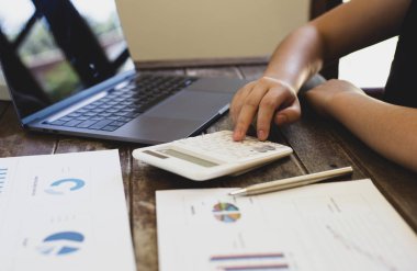 Finans ve finans muhasebecileri hesaplamak için bir hesap makinesi kullanarak gelir ve giderleri özetliyor, iş adamı