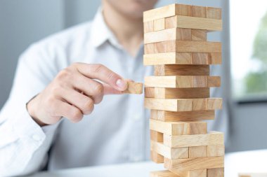 İş adamları ahşap oyunlar oynar, bir işletmenin ortalama yatırım değerini böler ve riskleri ortaklaşa yönetir, alternatif risk planı ve iş stratejisi.