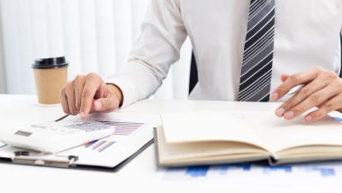 İşadamı iş yerindeki grafikler ve dizüstü bilgisayarlar, İş Finansmanı Bankacılık ve vergi sistemi kavramı ile piyasa verilerini hesaplıyor ve analiz ediyor.