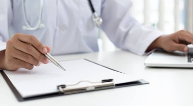 Doktor hasta bilgilerini kaydetmek ve modern bir hastane, acil yardım ve sağlık hizmetleri konseptine tanı koymak için bir belgeye yazmak için dizüstü bilgisayar kullanır..