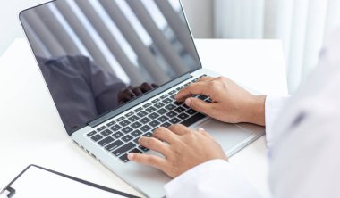 Doktor hasta bilgilerini kaydetmek ve modern bir hastane, acil yardım ve sağlık hizmetleri konseptine tanı koymak için bir belgeye yazmak için dizüstü bilgisayar kullanır..