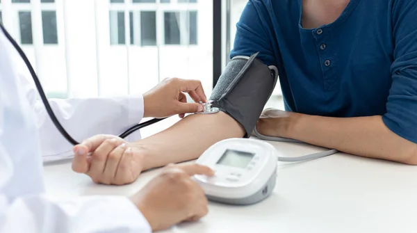 女性医師は血圧計と聴診器を使用して脈拍を測定します現代の病院の医療研究室で患者の病気を診断します — ストック写真