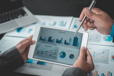 Beyin fırtınası ekibi, pazarlamacılar ve finans danışmanları müşteri ihtiyaçları, bilgisayar ve iş konsepti için tablet teknolojisini karşılayacak stratejiler planlamak ve planlamak için grafikleri tartışıyor..