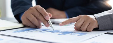 Beyin fırtınası ekibi, pazarlamacılar ve finans danışmanları müşteri ihtiyaçlarını karşılayacak stratejiler planlamak ve analiz etmek için çizelgeleri, iş başarısı kavramını tartışıyor..