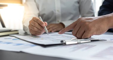 Beyin fırtınası ekibi, pazarlamacılar ve finans danışmanları müşteri ihtiyaçlarını karşılayacak stratejiler planlamak ve analiz etmek için çizelgeleri, iş başarısı kavramını tartışıyor..