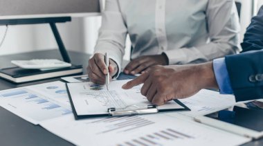 Beyin fırtınası ekibi, pazarlamacılar ve finans danışmanları müşteri ihtiyaçlarını karşılayacak stratejiler planlamak ve analiz etmek için çizelgeleri, iş başarısı kavramını tartışıyor..