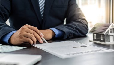 Satış müdürü ya da emlakçı evin anahtarlarını ve sigortalarını müşteriye, emlak hizmetlerine ve sigorta konseptine vermeye hazırlanır..