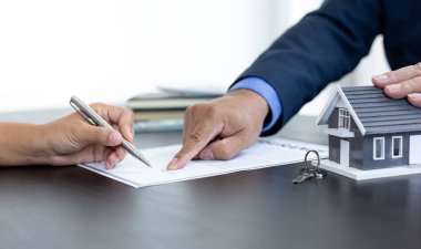 Emlakçı ya da satış müdürü, ev satın alma anlaşmalarını sigorta ile imzalayan müşterilere satın alma sözleşmesini imzalama şartlarını ve şartlarını önerdi.