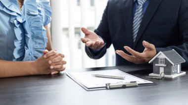 Emlakçı ya da satış müdürü, ev satın alma anlaşmalarını sigorta ile imzalayan müşterilere satın alma sözleşmesini imzalama şartlarını ve şartlarını önerdi.