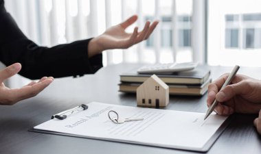 Emlakçı ya da satış müdürü, ev satın alma anlaşmalarını sigorta ile imzalayan müşterilere satın alma sözleşmesini imzalama şartlarını ve şartlarını önerdi.