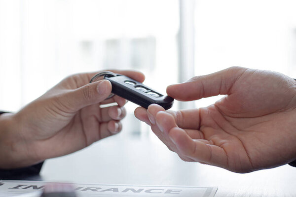 Car sales representative or sales manager submits a car key to a client who has approved financial loans with the company, Approval of financial and banking loans concept.