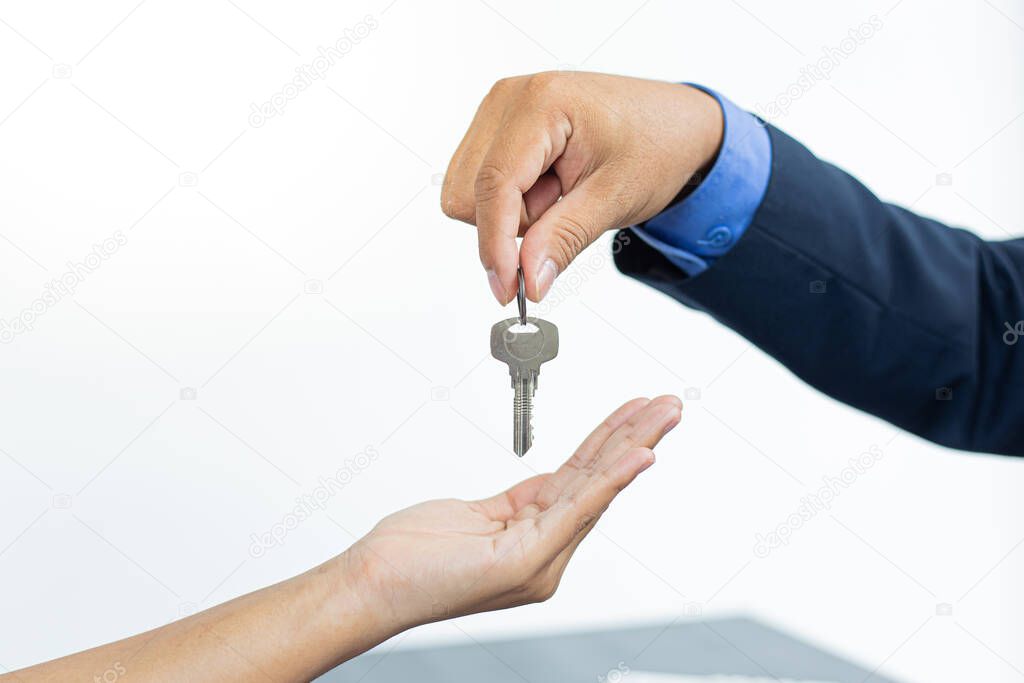 Sales manager or real estate agent holds the key handing it to the customer after signing the house purchase contract with home insurance, Trading of mortgages and insurance concept.