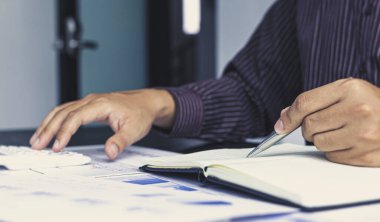 Muhasebe işadamları hesap makineleri ve grafiklerle şirket gelir vergisini hesaplıyor, mali ve bankacılık kar analizi kavramı.