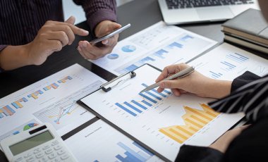 İş dünyası ekibi toplantısı mevcut, iş adamları ve yatırımcılar çalışmalarını finans yöneticileri, finans muhasebe ve Tex 'e sunmak üzere yıllık gelir veri grafiklerini inceliyor ve analiz ediyorlar.