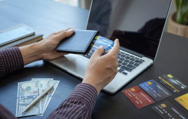 İş adamları internet üzerinden kredi kartı ödemelerini, teknoloji ve İnternet 'te rahatlığı, online alışveriş ve online bankacılık kavramını kullanarak online alışverişleri kaydetmek için dizüstü bilgisayar kullanıyorlar..
