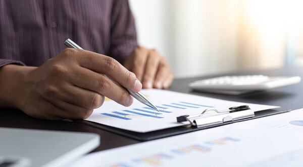 Independent financial businessmen calculate the client's annual income and analyze the market in-depth with office graphs, Income Tax Management and Financial Accounting concept.