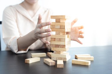 İşadamları yüksek bir kuleye tahta bloklar yerleştirerek yüksek bir ahşap kuleyi korumak için yüksek riskli ahşap bloklar konsepti de içerir..