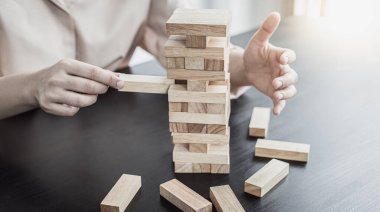 İşadamları yüksek bir kuleye tahta bloklar yerleştirerek yüksek bir ahşap kuleyi korumak için yüksek riskli ahşap bloklar konsepti de içerir..