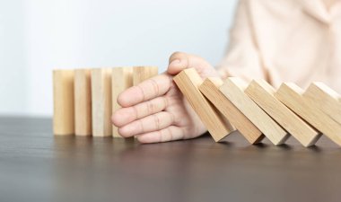 İş kadını sürekli risk almak, sürekli hasar azaltmak, iş dominosu başarısızlıklarını durdurmak için domino taşının üzerine düşen elleri durdurur..