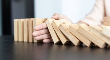 İş kadını sürekli risk almak, sürekli hasar azaltmak, iş dominosu başarısızlıklarını durdurmak için domino taşının üzerine düşen elleri durdurur..