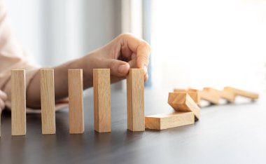İş kadını sürekli risk almak, sürekli hasar azaltmak, iş dominosu başarısızlıklarını durdurmak için domino taşının üzerine düşen elleri durdurur..