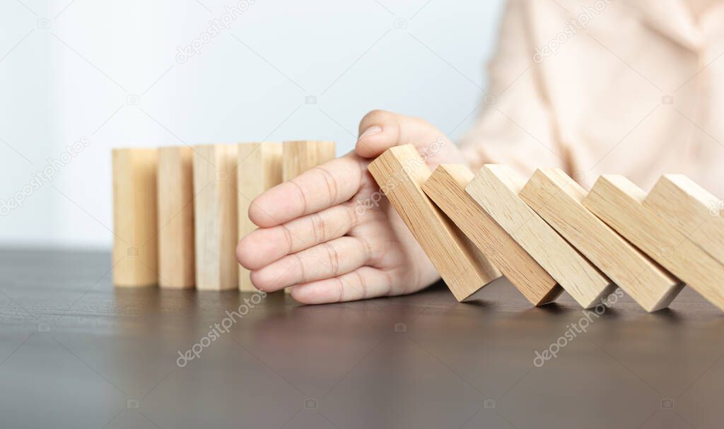 Businesswoman stops hands falling over domino to stop risk continuously, Continuous damage reduction, Stop business domino failures concept.