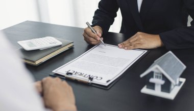 Emlakçı ev satın alma anlaşmasının şartları hakkında konuştu ve müşteriden sözleşmeyi yasal hale getirmek için belgeleri imzalamasını istedi, ev satışları ve ev sigortası kavramı.