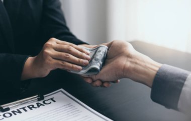 İşadamları, yasadışı arazi ve gayrimenkul, iş dolandırıcılığı ve sosyal adaletsizlik, yolsuzluk ve rüşvet kavramını satın almak için sözleşmeler imzalayan çalışanlara dolar dağıtıyor.